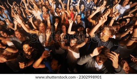 Music, dance and party with crowd at concert for rock, live band performance or festival. New year, energy and disco with audience of fans listening at celebration for techno, rave or nightclub event Royalty-Free Stock Photo #2302998901
