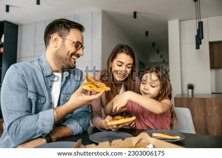 Mom, dad and daughter are eating together at home. Happy family enjoying at home.Family eating pizza at home.