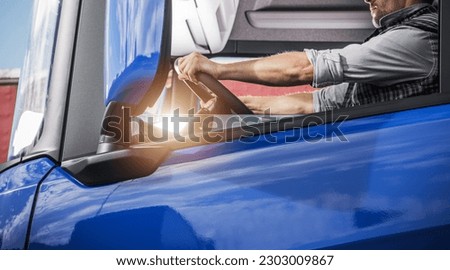 European Caucasian Semi Truck Driver in His 40s Behind the Wheel Side View. Euro Cargo Transportation. Royalty-Free Stock Photo #2303009867