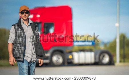 Necessary Truck Stop Break . Caucasian Semi Truck Driver Taking Short Walk Along Parking Lot. Transportation Industry Safety Theme. Royalty-Free Stock Photo #2303009873