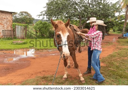couple saddling the horse to ride