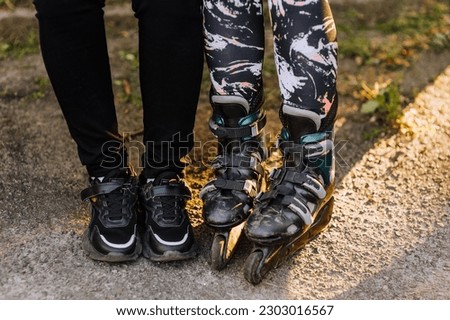 Two girlfriends are sitting on a park bench in roller skates and sneakers, preparing for sports skating. Photography, portrait, sport.