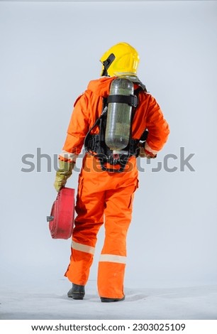Vertical picture of the firefighter stood tall and confident adorned in a bright yellow helmet that signified his role as a guardian against the raging flames on white background.