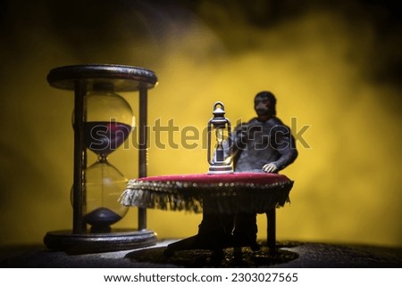 Time concept. Man sitting on table with hourglass. Abstract hourglasses with smoke and lights on a dark background. Surreal decorated picture