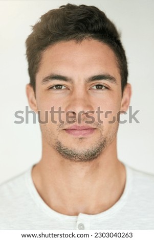 Portrait, face and headshot of man in studio, isolated white background and posing with casual attitude. Handsome young guy, serious male person and pose for ID photo, passport picture and confidence