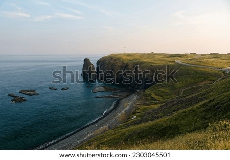 Idyllic coastal scenery of beautiful Cimei Island, in Penghu County, Taiwan, with wave-cut platforms and a sea stack by the rugged seaside cliff and the sky tinted by sunlight on a sunny summer day Royalty-Free Stock Photo #2303045501
