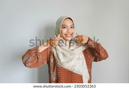 Beautiful smiling Asian woman in traditional muslim dress showing Korean heart with two fingers crossed, express joy and positivity isolated over white background