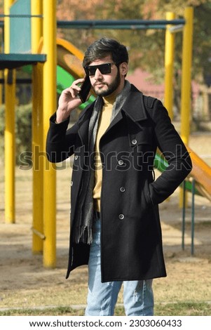 Young man talking on mobile phone while standing in a park in islamabad, Pakistan.