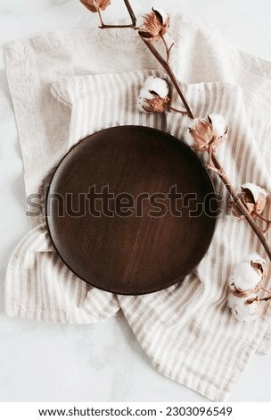 Wooden Plate mockup, linen napkins and cotton flowers top view on marble background. Eco friendly empty table place setting .Space for text or menu .Business food brand template. 