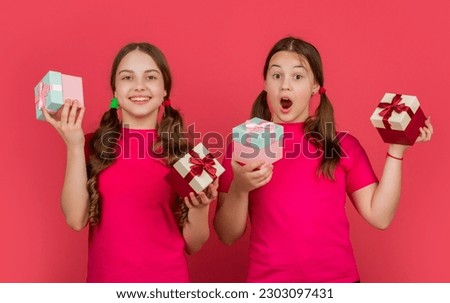 amazed children with present boxes on red background