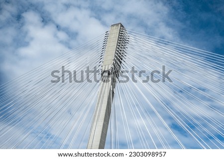 Modern bridge pylon against a blue sky. Detail of the multi-span cable-stayed bridge. Linear perspective view of a white cable-stayed suspension Alex Fraser Bridge in BC. Nobody, selective focus Royalty-Free Stock Photo #2303098957