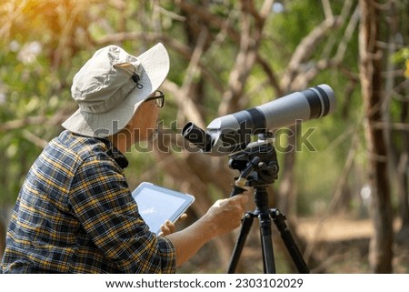 Middle-aged Asian man relaxing and happy by watching birds in the wild on vacation