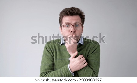The European young man, in shock, covers his mouth with his hands, thinking, No, this is impossible. Royalty-Free Stock Photo #2303108327