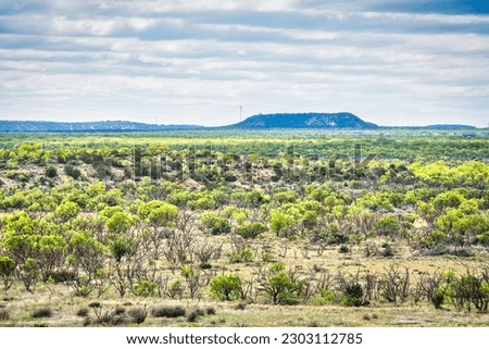 A picturesque landscape of rolling hills, lush grasslands and a distant horizon stretch across the natural beauty of San Angelo State Park in Texas. Royalty-Free Stock Photo #2303112785