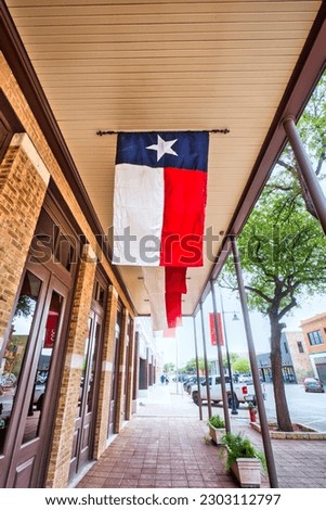 A bustling street in Abilene, Texas with the exterior of a Texas Star Trading building displaying a hanging Texas flag.