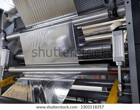 Roll of aluminum foil for food packaging on the automatic packing machine in food product factory. Royalty-Free Stock Photo #2303118357