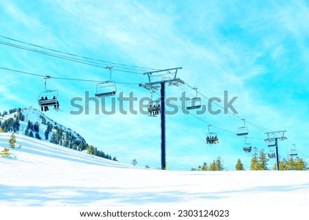 Skiers riding a chairlift on a sunny winter day at Mammoth Ski Resort. Royalty-Free Stock Photo #2303124023