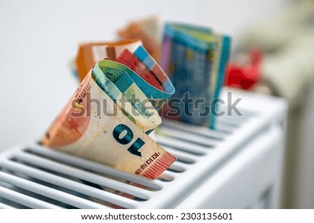 euro banknotes in a central heating radiator, the concept of expensive heating costs, close-up Royalty-Free Stock Photo #2303135601