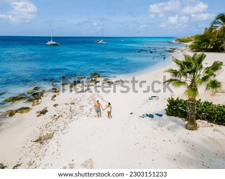 Eagle Beach Aruba, Palm Trees on the shoreline of Eagle Beach in Aruba, a couple of men, and a woman on the beach of Aruba Royalty-Free Stock Photo #2303151233