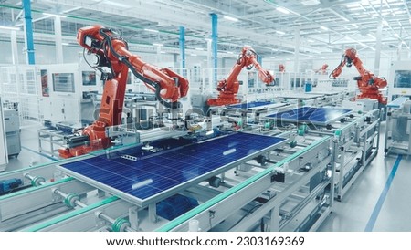 Orange Industrial Robot Arm at Production Line at Modern Bright Factory. Solar Panels are being Assembled on Conveyor. Automated Manufacturing Facility Royalty-Free Stock Photo #2303169369