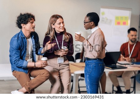 Happy diverse colleagues have fun at lunch break in office, smiling multiracial employees laugh and talk  drinking coffee Royalty-Free Stock Photo #2303169431