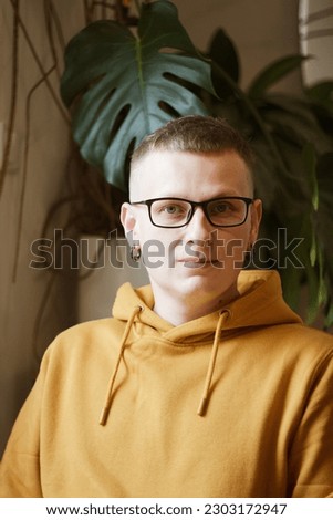 Portrait of smiling European millennial man with glasses looking at camera sitting in café or coffeeshop, happy young male in glasses posing for picture working at laptop or studying out in coffee