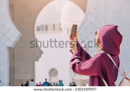 With her camera in hand, a curious visitor explores the intricate details of the Sheikh Zayed Grand Mosque in Abu Dhabi