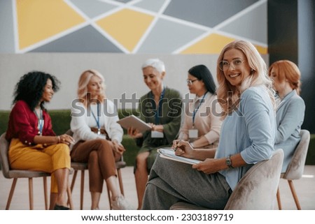 Happy mature woman looking at camera while visiting group training class for females Royalty-Free Stock Photo #2303189719
