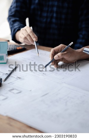The home design architects are reviewing the house plan draft, the project commissioned by the client, and the custom design before delivery. Interior design and decoration ideas. Royalty-Free Stock Photo #2303190833