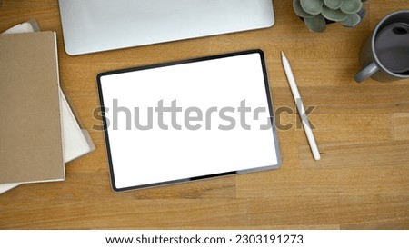 Top view image of a workspace with digital tablet white screen mockup, stylus pen, and accessories on wooden background.