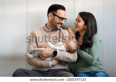 Portrait of parents and newborn baby. Father and mother kiss and hug a beautiful newborn child. . Royalty-Free Stock Photo #2303197125