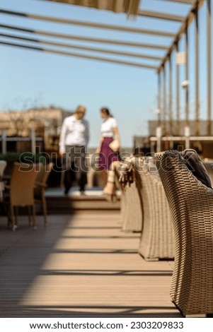 Outdoor empty restaurant terrace with unrecognizable staff on the background