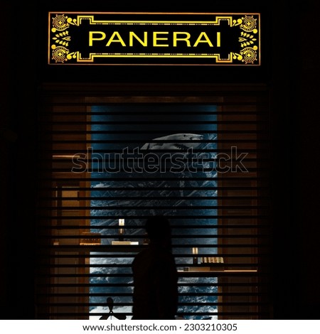 A man stand in front of the store at night