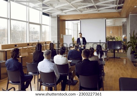 Businessman giving report or presentation to business colleagues. Professional coach consulting, training, explaining strategy to interested people, giving educational workshop in conference room Royalty-Free Stock Photo #2303227361