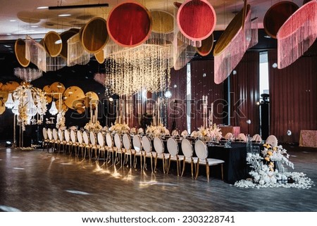 Luxury wedding reception. Table setting, setup. Banquet decoration composition flowers, candles in hall restaurant. Table covered black tablecloth. Trendy decor large chandelier for a birthday party. Royalty-Free Stock Photo #2303228741