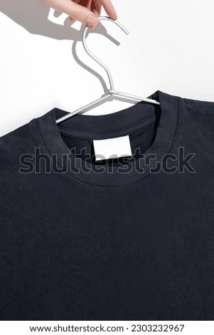 Black t-shirt with blank label on a clothes rack. Ecology concept. Mockup.