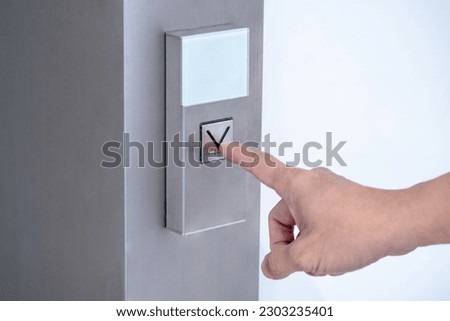 Forefinger pressing on button down of elevator (lift) in office building.