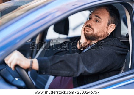 Young hispanic man driving car with desperate expression at street Royalty-Free Stock Photo #2303246757