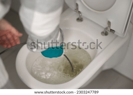 Man cleaning overflowing broken toilet. clogged toilet. Royalty-Free Stock Photo #2303247789