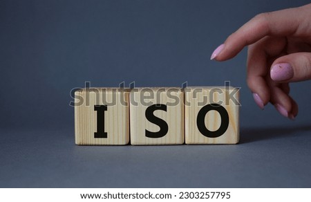ISO standards quality control symbol. Concept word ISO on wooden cubes. Businessman hand. Beautiful grey background. Business and ISO concept. Copy space.