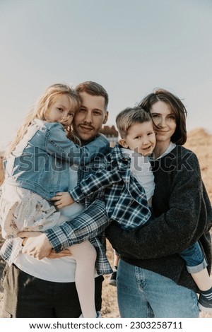 happy family spends time in nature. Son, daughter, dad and mom are hugging and laughing Royalty-Free Stock Photo #2303258711