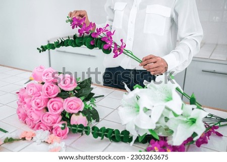 Arranging artificial flowers decoration at home, Young woman florist work making organizing diy artificial flower, craft and hand made concept. Royalty-Free Stock Photo #2303263675