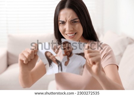 Upset woman ripping photo at home. Divorce concept