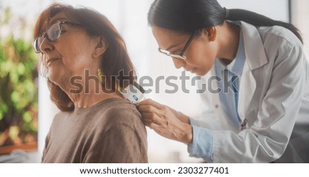 Middle Aged Female Passing a Medical Examination by a Young General Practitioner in a Modern Clinical Trial Room. Dermatologist Diagnosing the Patient Before Appointing a Skin Biopsy Royalty-Free Stock Photo #2303277401