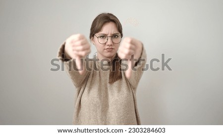 Young blonde woman doing negative gesture with thumbs down over isolated white background
