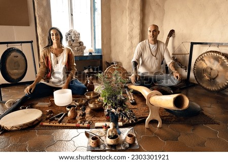 Couple sitting with their sound therapy instruments, looking and smiling at camera. Relaxation and meditation. Sound therapy, alternative medicine. Royalty-Free Stock Photo #2303301921