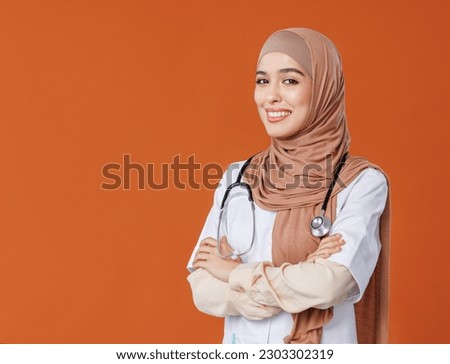 Professional woman doctor in muslim national hijab isolated  on orange background