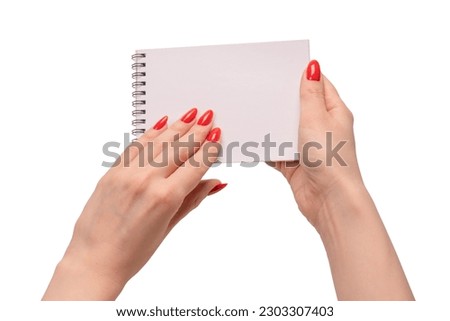 A notebook with empty white paper in woman hands with red nails. Copy space. 
