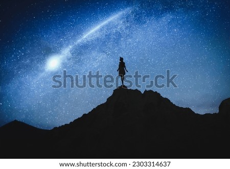 Silhouette of woman in mountains under starry sky at night
