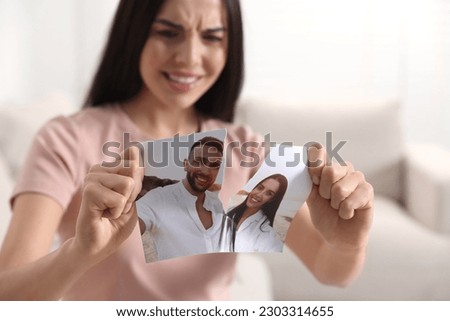 Upset woman ripping photo at home, selective focus. Divorce concept